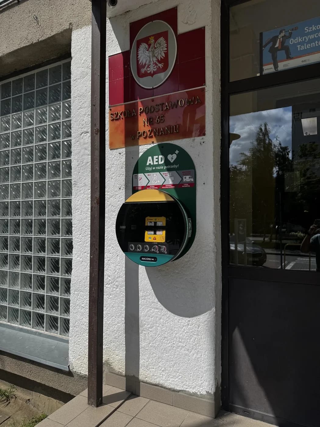 Szafka AED z ViVest przy wejściu do Szkoły Podstawowej nr 65 w Poznaniu